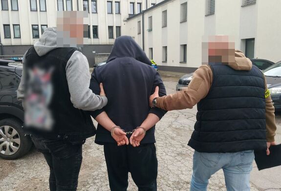 Policjanci prowadzą zatrzymanego mężczyznę.