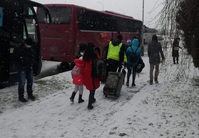 policjant idący z uchodźcami, w tle widać autokary